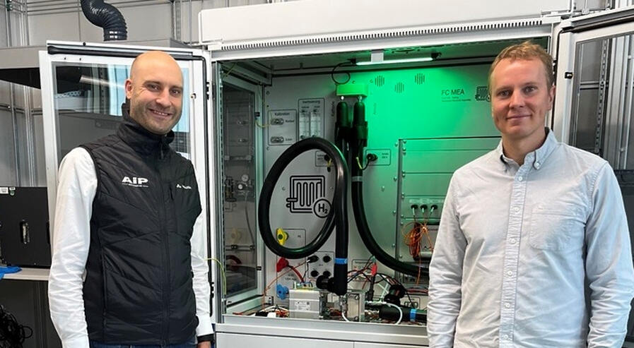 two persons in front of the fuel cell test bench