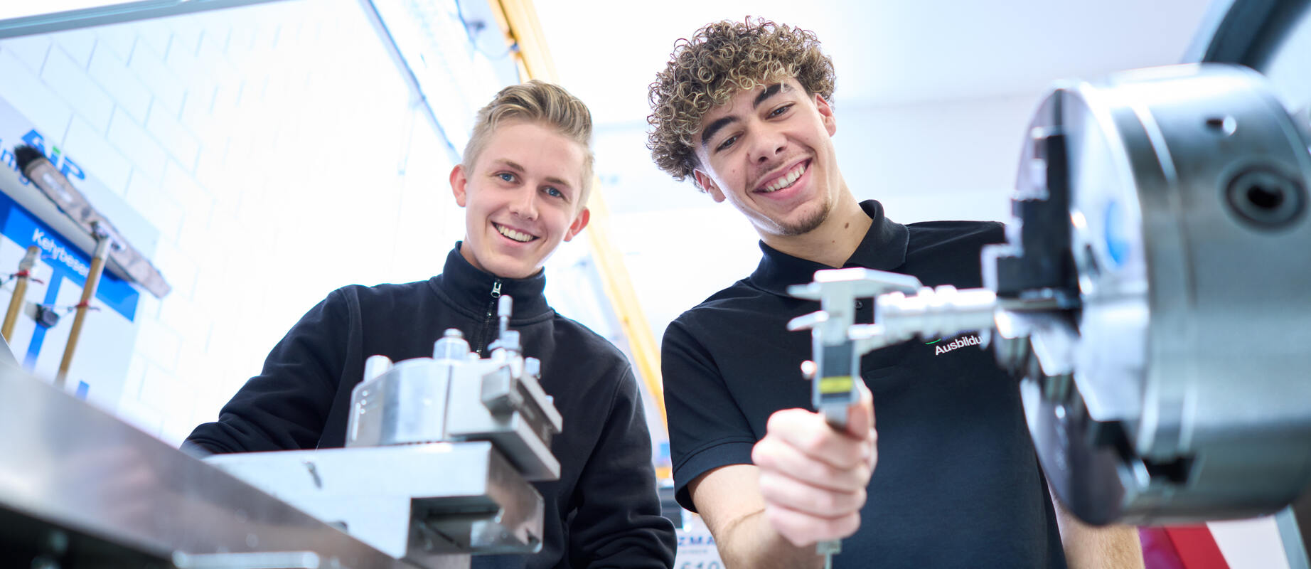 Zwei Auszubildende arbeiten gemeinsam an einer Drehmaschine. 