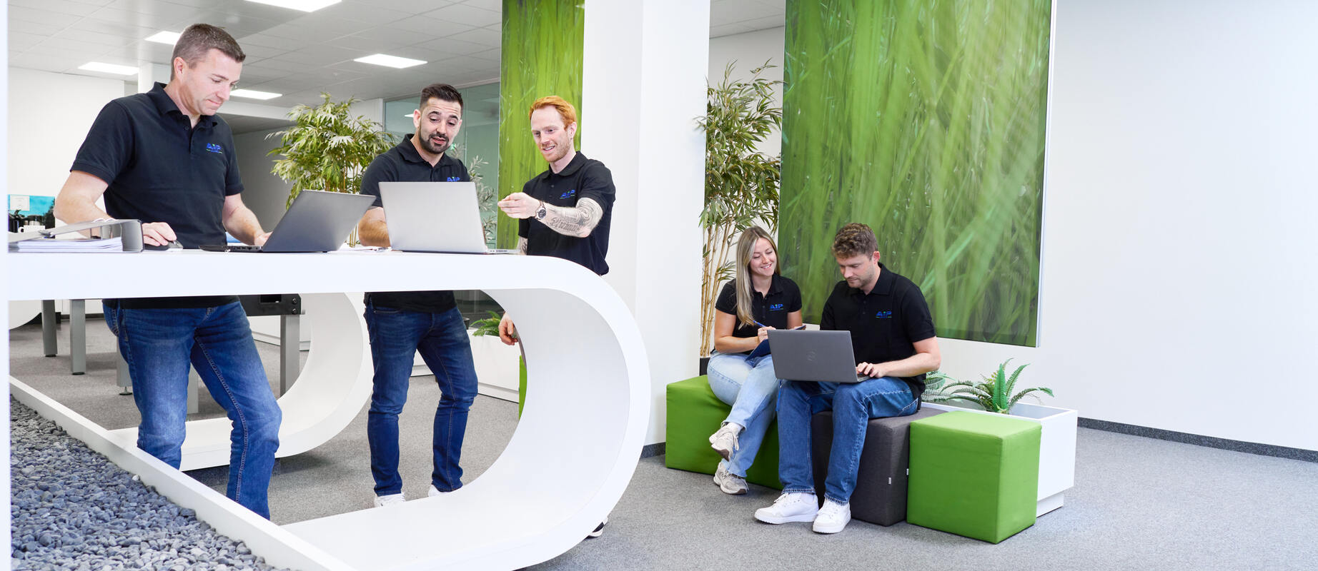 Fünf Mitarbeitende halten sich in einer Lounge auf und arbeiten in Kleingruppen.