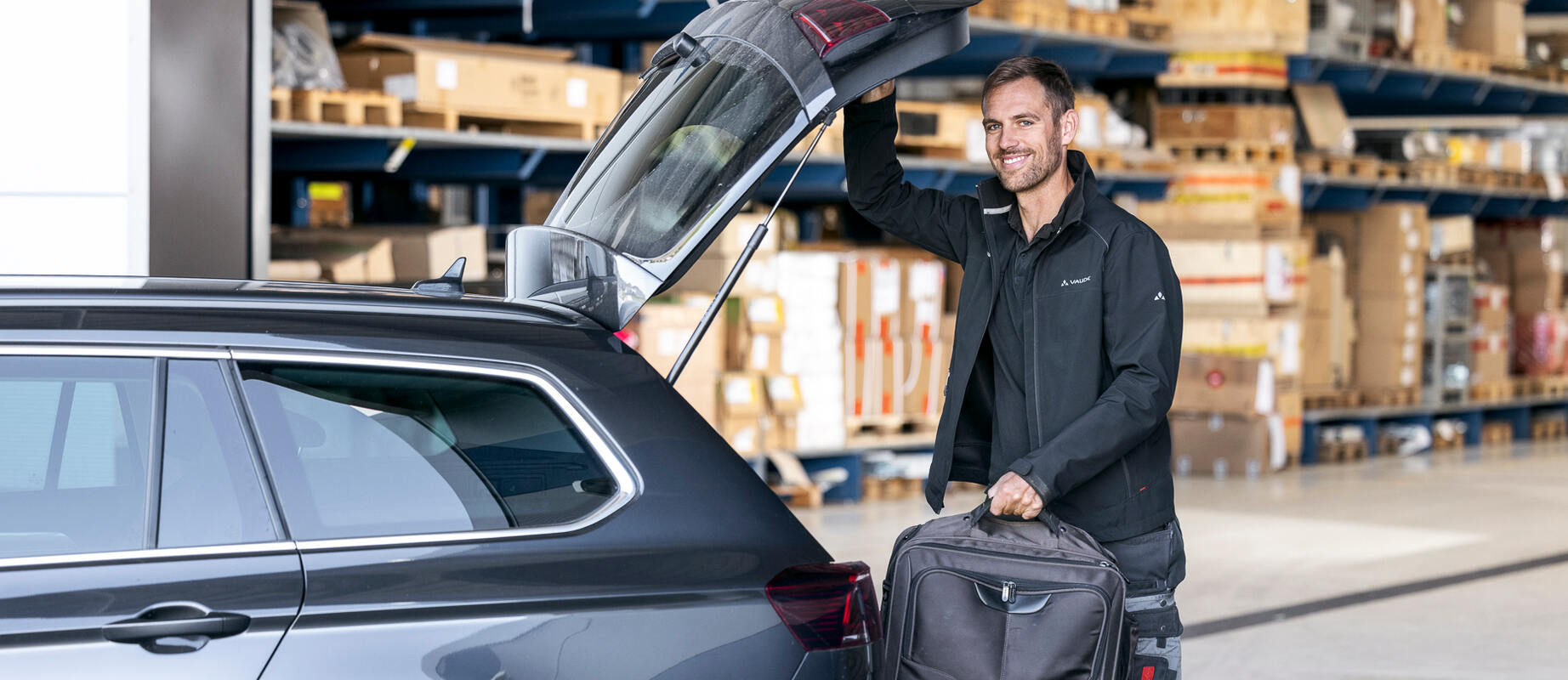 Servicemitarbeiter lächelt einen Kunden an, den man von hinten erkennt.