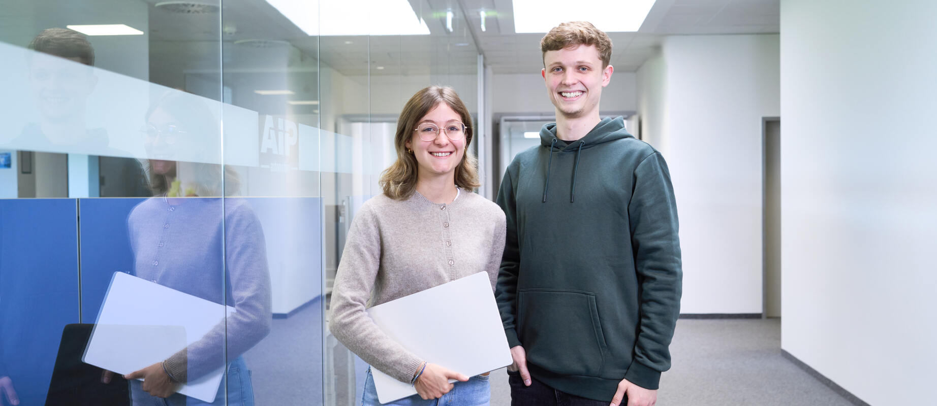 Servicemitarbeiter lächelt einen Kunden an, den man von hinten erkennt.