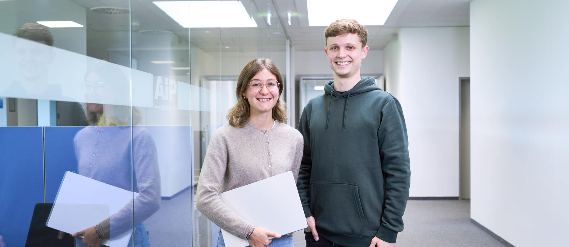 Servicemitarbeiter lächelt einen Kunden an, den man von hinten erkennt.