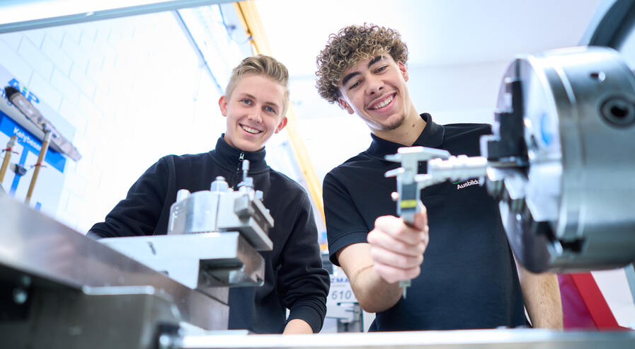 Zwei Auszubildende arbeiten gemeinsam an der Drehmaschine.
