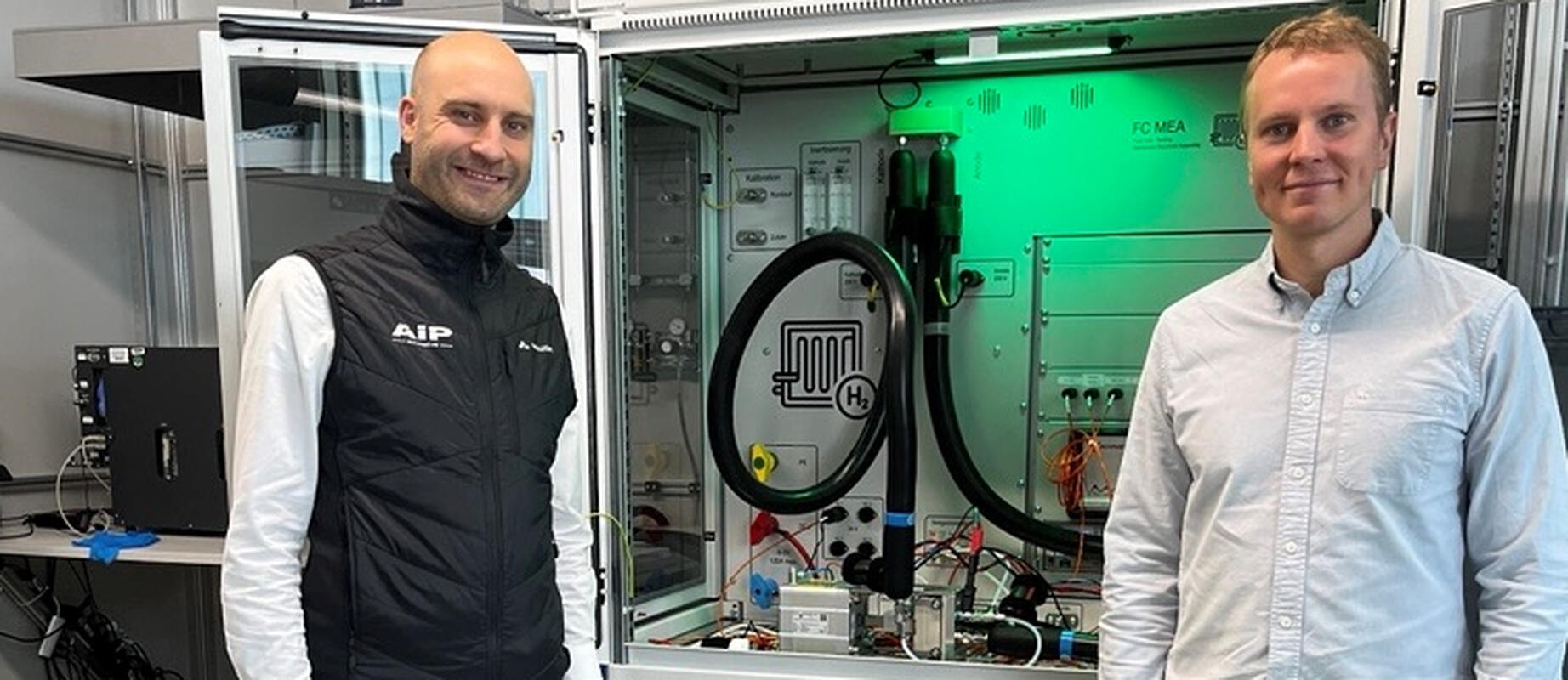Two people in front of fuel cell test bench