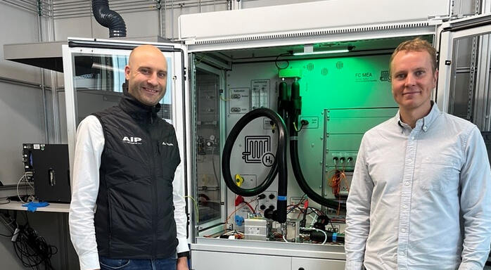 Two people in front of fuel cell test bench